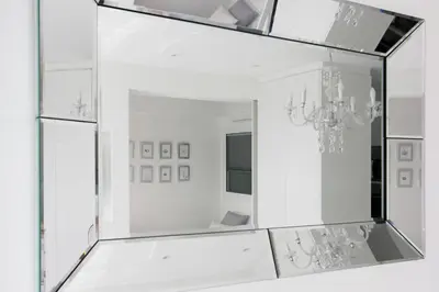 a mirror in a white room with a chandelier at The White Pearl Suite - beach front city centre with sea view. in Limassol