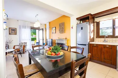 a kitchen and dining room with a table with a bowl of fruit at Villa Joan in Ayios Theodhoros