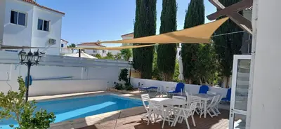 a patio with a pool and chairs and an umbrella at Villa Kiveli in Ayia Napa