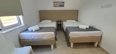a room with three beds and a window at CHRIS'S HOLIDAY APT - AYIA NAPA in Ayia Napa