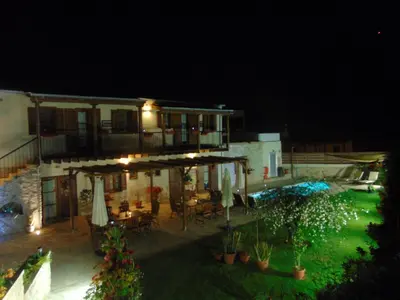a building with a patio with tables and umbrellas at night at Charalambos Holiday Cottage in Kalavasos