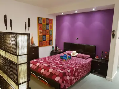 a bedroom with a bed with a purple wall at Sylvias art studio apt in Ayia Napa