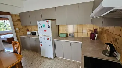 a kitchen with a white refrigerator and a table at Family Nest In The Heart Of Limassol in Limassol