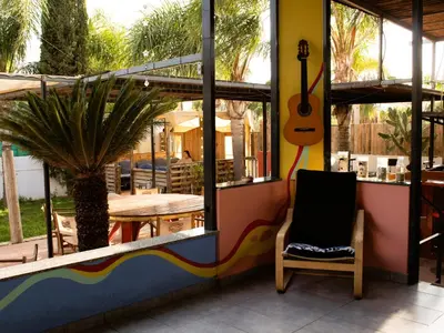 a room with a guitar and a chair and a table at House of Nissus Hostel in Ayia Napa