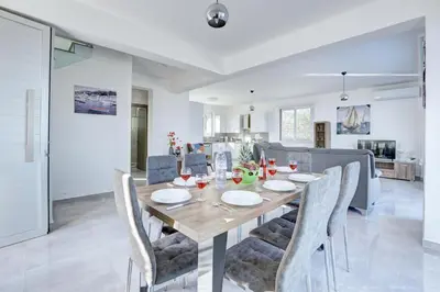 a dining room and living room with a table and chairs at Aetopetra Villa in Protaras