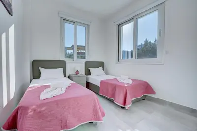 two beds in a white room with windows at Aetopetra Villa in Protaras