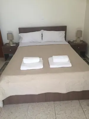 a bed with two white towels on it with two night stands at Artemis House in Limassol