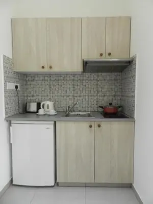 a kitchen with wooden cabinets and a white refrigerator at Evabelle Napa Hotel Apartments in Ayia Napa