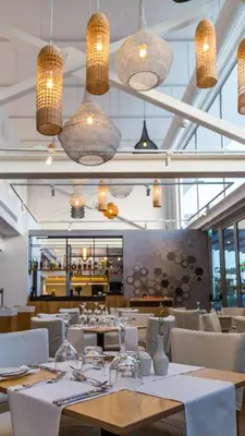 a dining room with tables and chairs and lights at Protaras Plaza Hotel in Protaras
