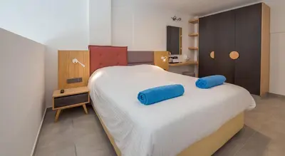 a bedroom with a bed with blue pillows on it at Protaras Plaza Hotel in Protaras
