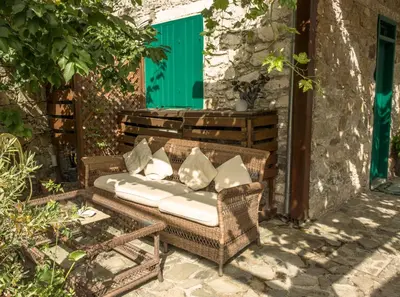 a wicker sofa with pillows sitting on a patio at Anastou's Traditional House in Kalopanayiotis