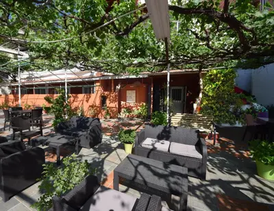 a patio with black chairs and tables under a tree at Christys Palace Hotel in Pedoulas