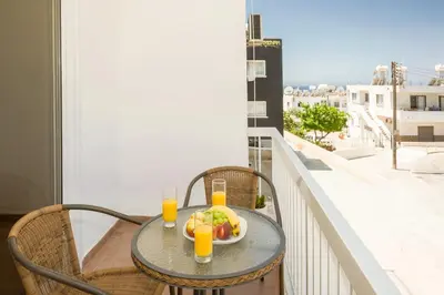 a table with a bowl of fruit and drinks on a balcony at MyNapa Apartments in Ayia Napa