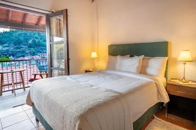 a bedroom with a large bed and a balcony at Ambelikos Traditional Agrohotel in Potamitissa