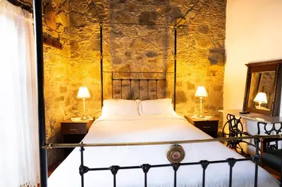 a bed in a room with two lamps on tables at Ambelikos Traditional Agrohotel in Potamitissa