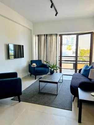 a living room with blue couches and a table at Pigeon Beach Hotel Apartments in Limassol