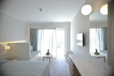 a white bedroom with a bed and a window at Sunrise Gardens Aparthotel in Protaras