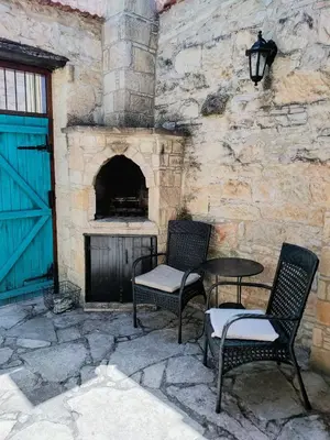a patio with two chairs and a table and a stone fireplace at Stou Kir Yianni in Omodos