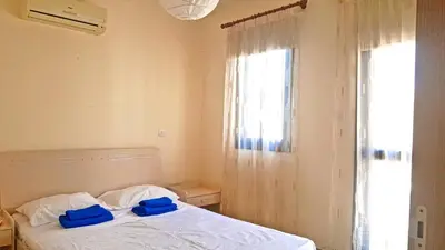 a bedroom with a bed with blue cushions and a window at Kapparis town house in Paralimni