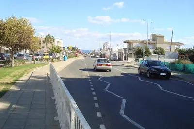 two cars driving down a road with a fence at Lucky 5 in Paralimni