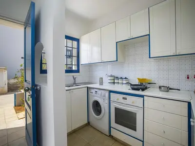 a kitchen with white cabinets and a washing machine at Protaras Villa Stef in Protaras