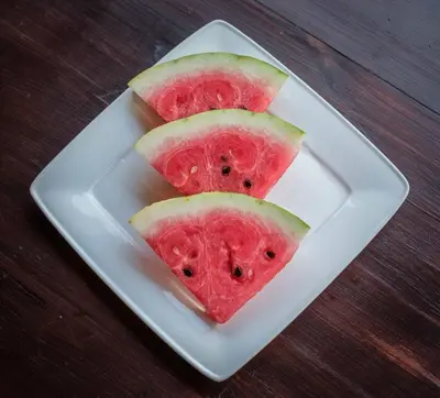 three slices of watermelon on a plate on a table at Teacher's House in Maroni