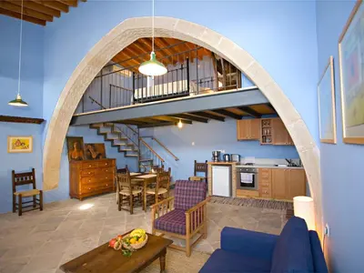 a living room with an archway and a dining room and kitchen at Evkarpos Country House in Psematismenos