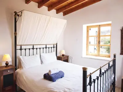 a bedroom with a large bed with white sheets and a window at Evkarpos Country House in Psematismenos
