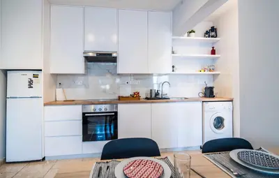 a kitchen with white cabinets and a table with chairs at Anemomylos guesthouse in Paralimni