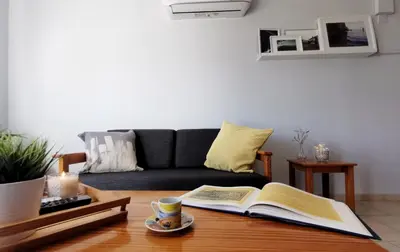 a living room with a couch and a coffee table with an open book at Anemomylos guesthouse in Paralimni