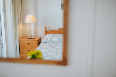 a mirror reflecting a bedroom with a bed and a lamp at Lazaros Centre Apartment in Larnaka