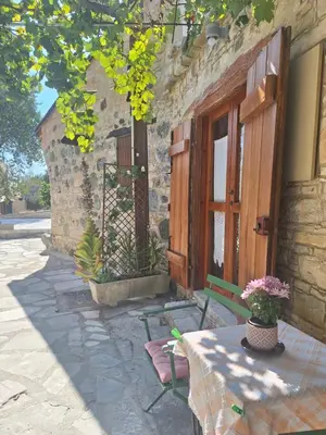 a table and a bench in front of a building at Eleni's Cottage in Apsiou