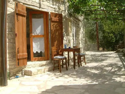 a table and chairs sitting outside of a house at Eleni's Cottage in Apsiou