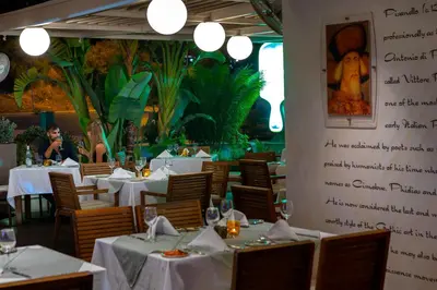 a restaurant with white tables and chairs and a wall with writing at Melissi Beach Hotel & Spa in Ayia Napa