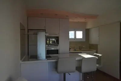 a kitchen with white cabinets and a table and chairs at Двуспальная квартира возле дасуди in Limassol
