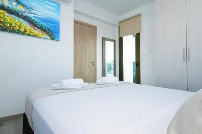 a white bedroom with a bed and a painting on the wall at Villa Calliopi in Protaras