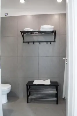 a bathroom with a toilet and a shelf with towels at Idyllic studio with private pool in Nicosia