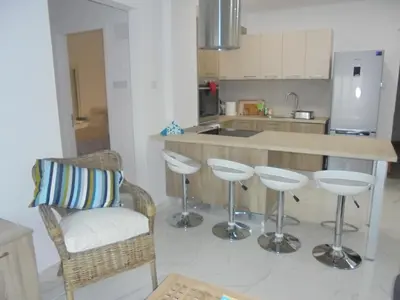 a kitchen with a bar with stools and a counter at Kermia Court - Beach-front, modern 2 bedroom -sleeps 6 in Limassol