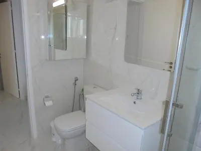 a white bathroom with a toilet and a sink at Kermia Court - Beach-front, modern 2 bedroom -sleeps 6 in Limassol
