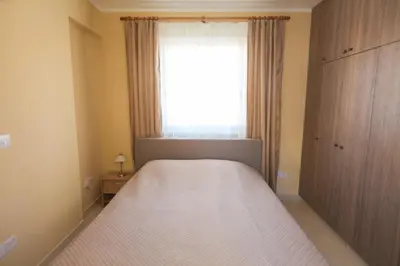 a bedroom with a bed and a large window at Carisa Livadia Gardens in Livadhia