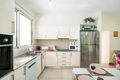 a kitchen with white cabinets and a stainless steel refrigerator at Villa Venus by Ezoria Villas in Pervolia
