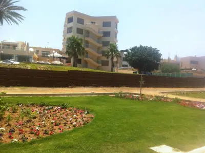 a park with a flower bed in front of a building at one bedroom apartment in Fig tree bay in Protaras