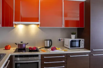 a kitchen with red cabinets and a microwave at one bedroom apartment in Fig tree bay in Protaras