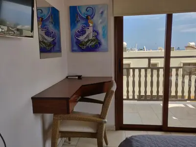 a desk and a chair in a room with a balcony at Elena Court Apartments in Ayia Napa