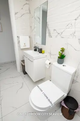a white bathroom with a toilet and a sink at Lazuli City & Seaview Apartments in Larnaka