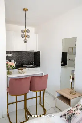 a kitchen with white cabinets and pink chairs at Lazuli City & Seaview Apartments in Larnaka