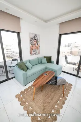 a living room with a blue couch and a table at Lazuli City & Seaview Apartments in Larnaka