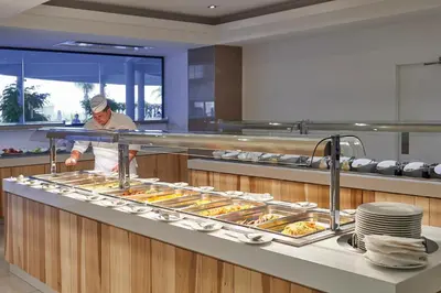 a man is preparing food in a kitchen at Sunrise Oasis Hotel & Waterpark in Protaras