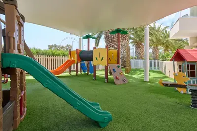 a playground with a slide in a yard at Sunrise Oasis Hotel & Waterpark in Protaras
