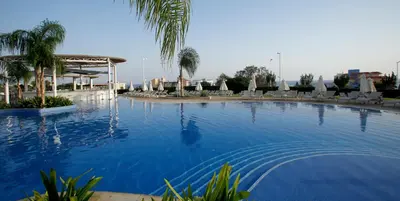 a large swimming pool with chairs and umbrellas at Sunrise Oasis Hotel & Waterpark in Protaras